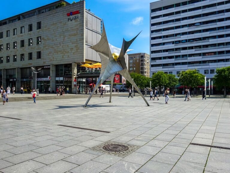 Escultura Moderna Em Uma Praca Da Cidade Com Predios Vks9geiKxTM