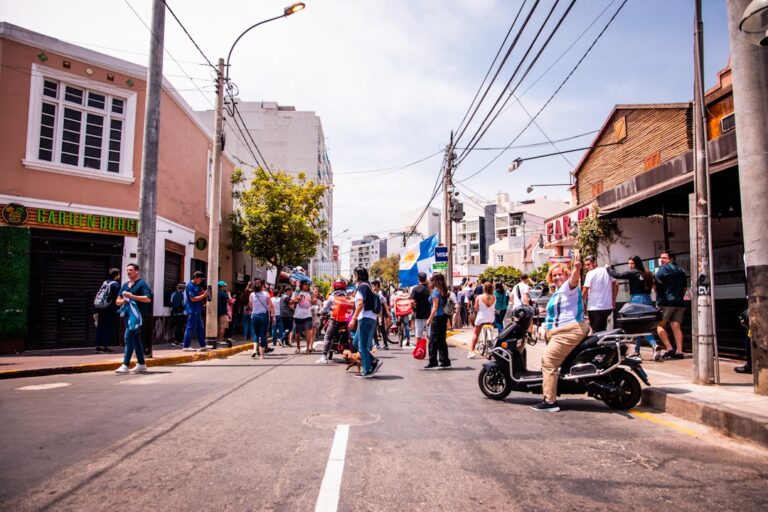 Um Grupo De Pessoas De Pe Ao Lado De Uma Rua arIRJkNvu_I