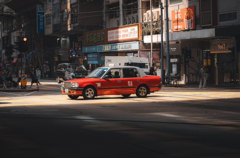 Taxi Vermelho Dirigindo Numa Rua Ensolarada Da Cidade sj98CADgI1Q