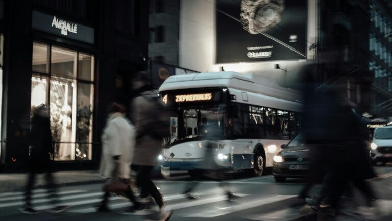 Blurred motion urban street scene with pedestrians and bus at zebra crossing.