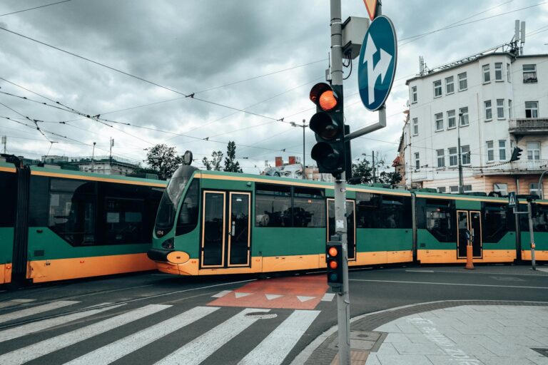 Green and yellow trams at a city intersection in Poznań, capturing urban transportation.