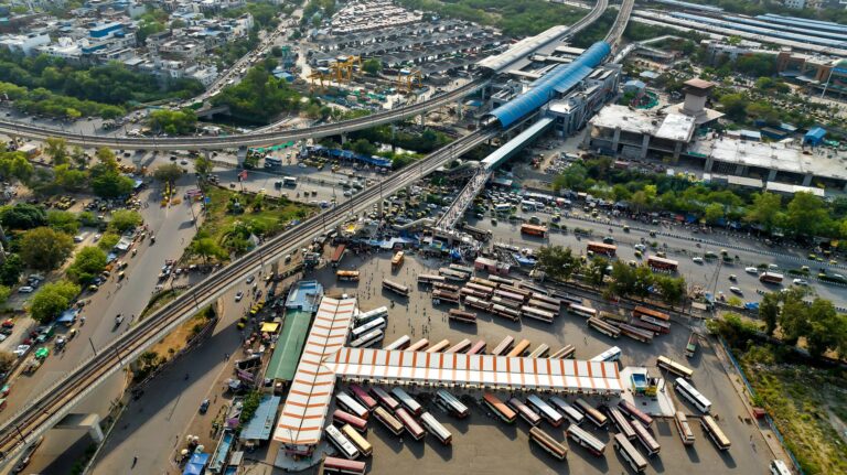 Aerial view of urban transport hub with multiple buses and highway bridges in daylight.