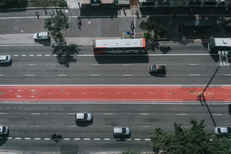 Aerial perspective of city traffic showcasing cars, buses, and bike lanes on a major roadway.