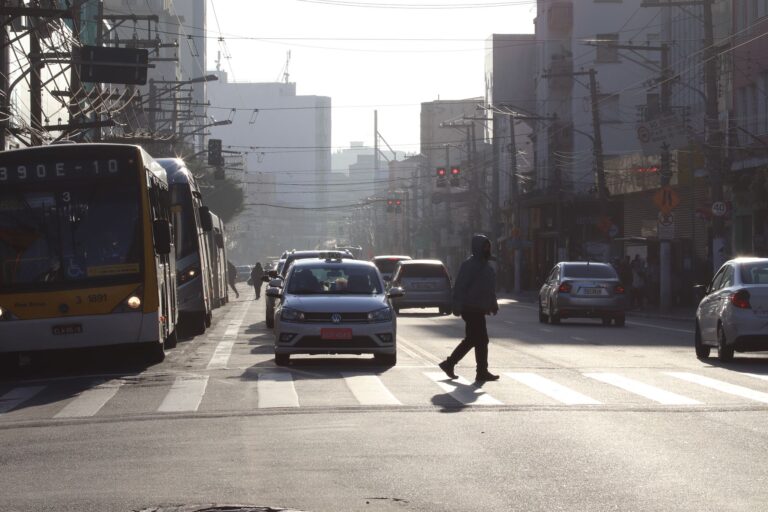 Busy São Paulo street with cars, bus and pedestrian crossing in urban setting.