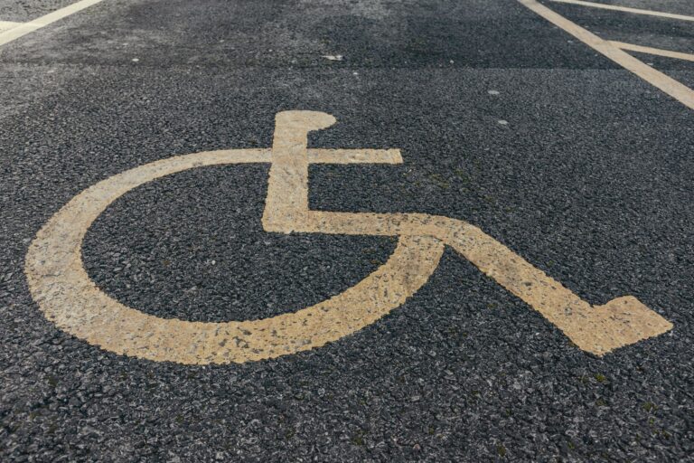 Close-up of a painted accessibility symbol on asphalt parking pavement.