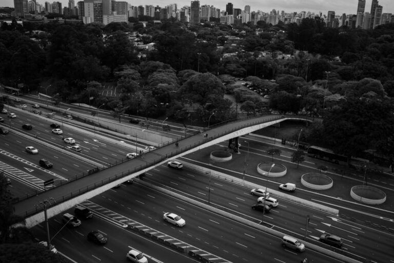 Black and white from above of modern wide roadway with moving vehicles in big town with modern buildings