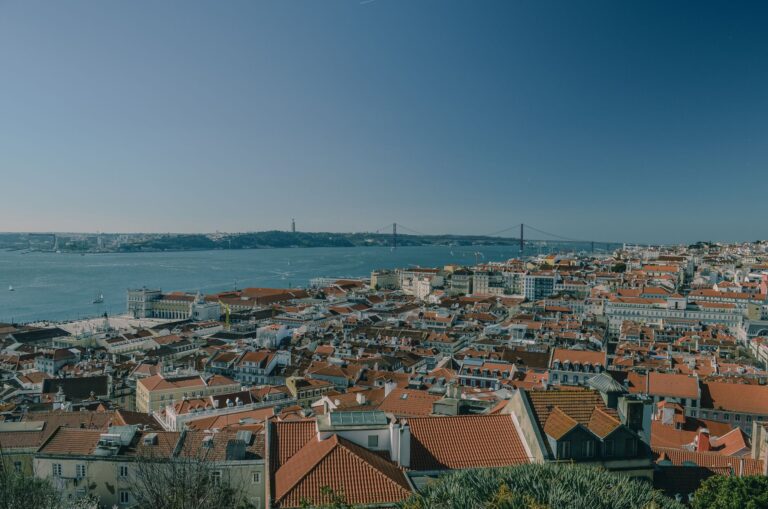 Scenic view of Lisbon's red rooftops and the Tagus River with the iconic 25 de Abril Bridge.